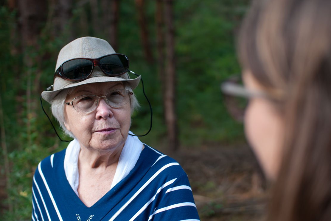 a lady in her mid 80's with a hat and sunglasses on it and blue white stripy sweater