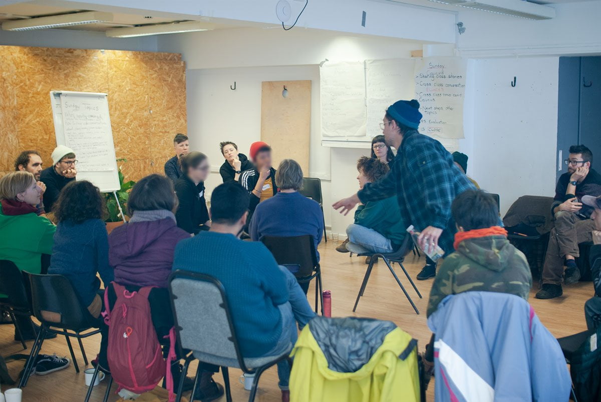 20 people sitting on chairs forming a circle. Four chairs in the middle where questions are fired. Fishbowl