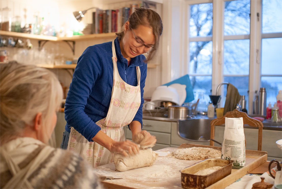 a young woman is kneading sourdough for bread on a big wooden board