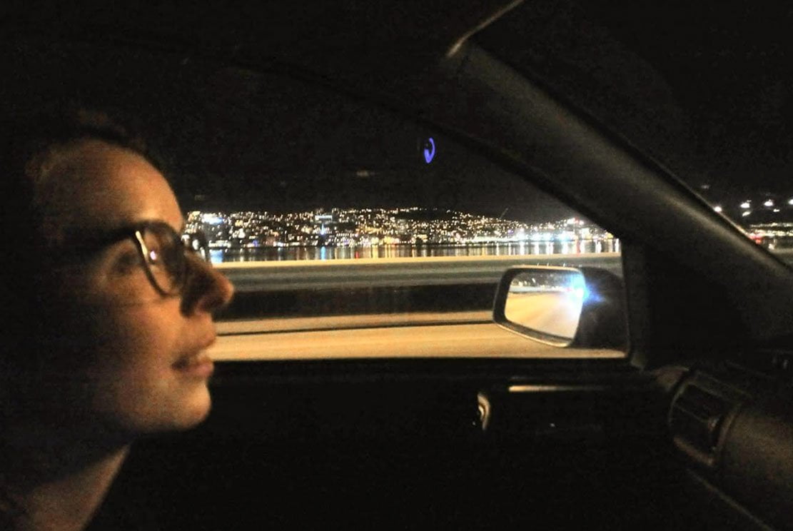 young women sitting on a car's passenger side entering city of Tromsø 