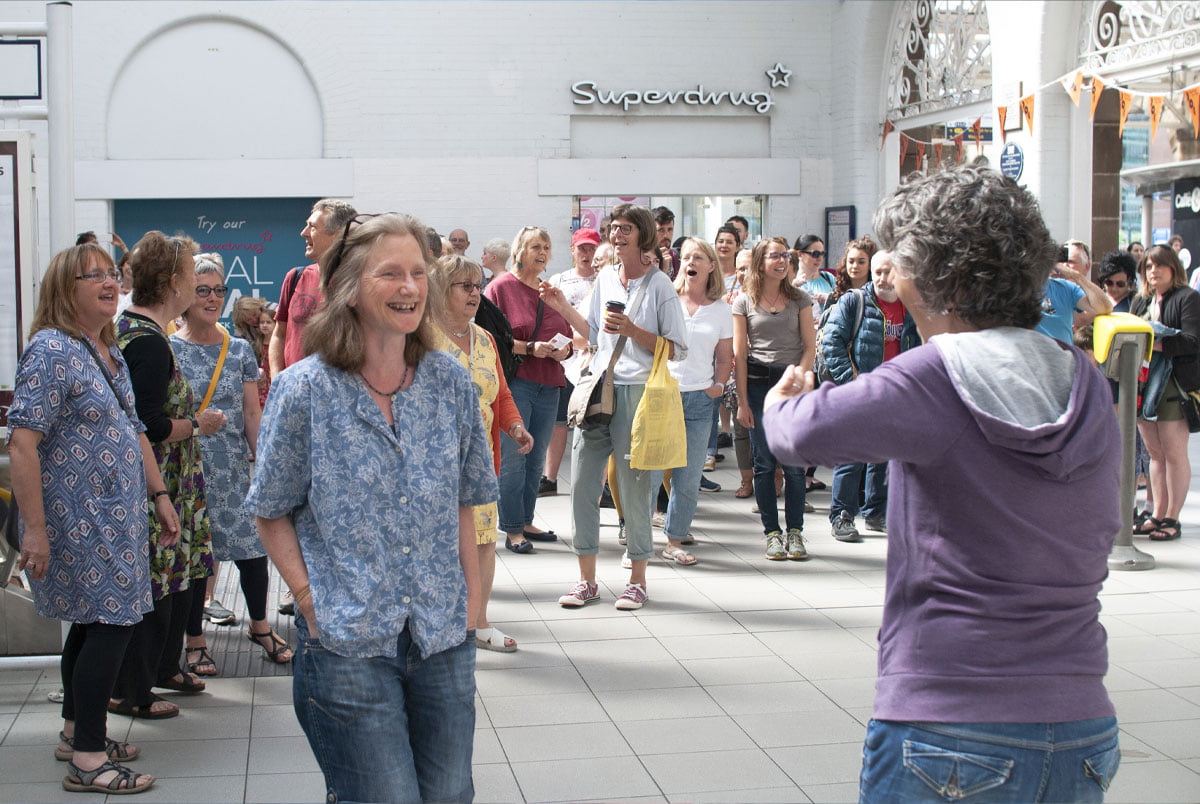 around-40-people-in-a-train-station-singing-in-a-harmony-as-one-choir,-unexpected-flash-mob